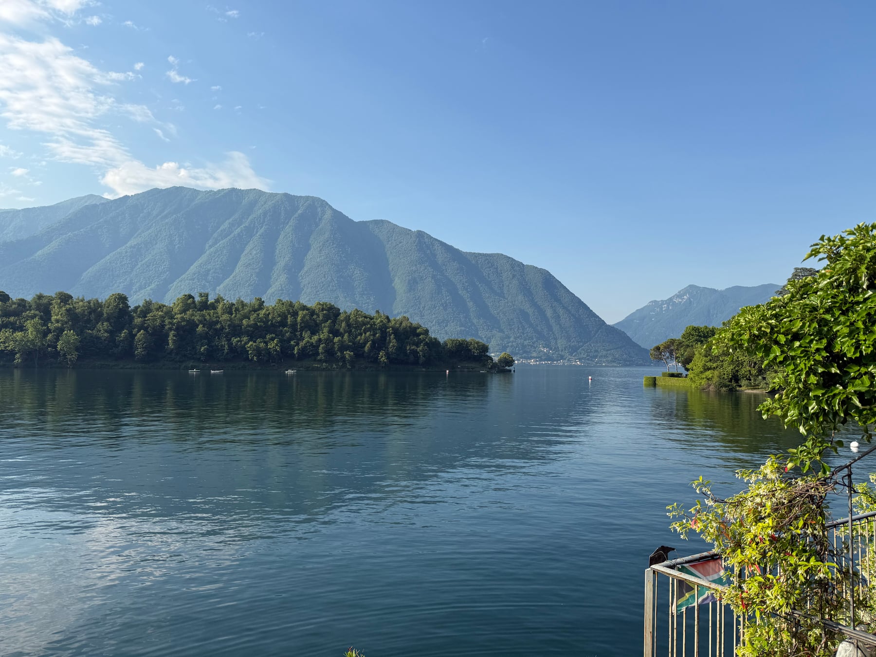 Lake Como with calm water and green mountains reflected in the distance